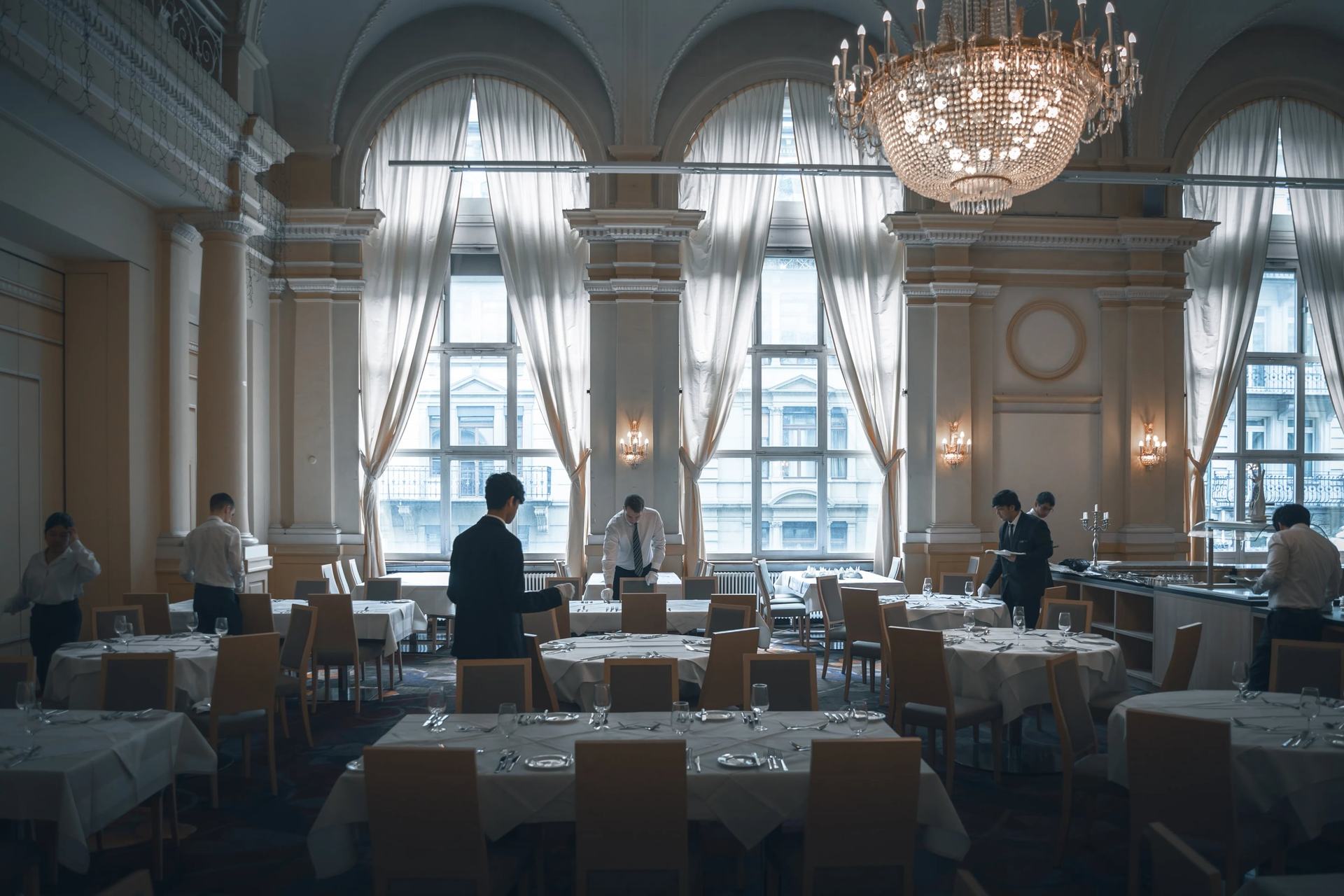 BHMS students preparing a grand chandeliered dining hall for fine-dining service