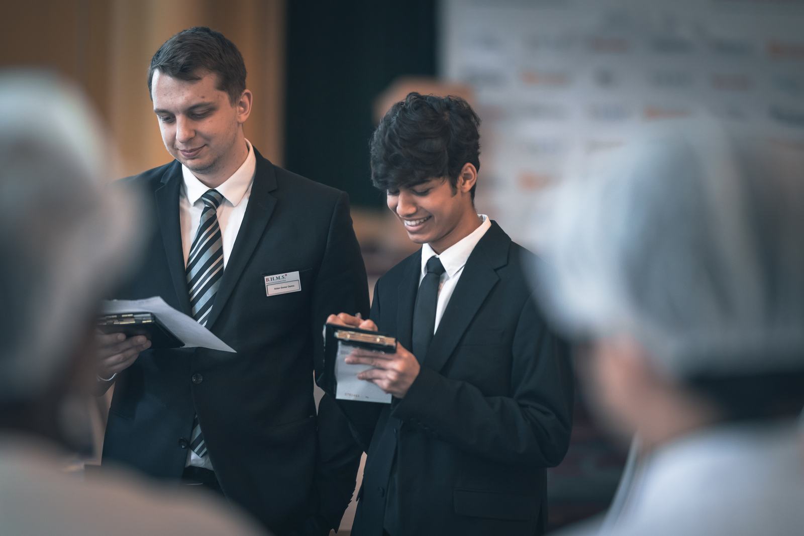 Two BHMS students in suits with name badges working a professional recruitment event